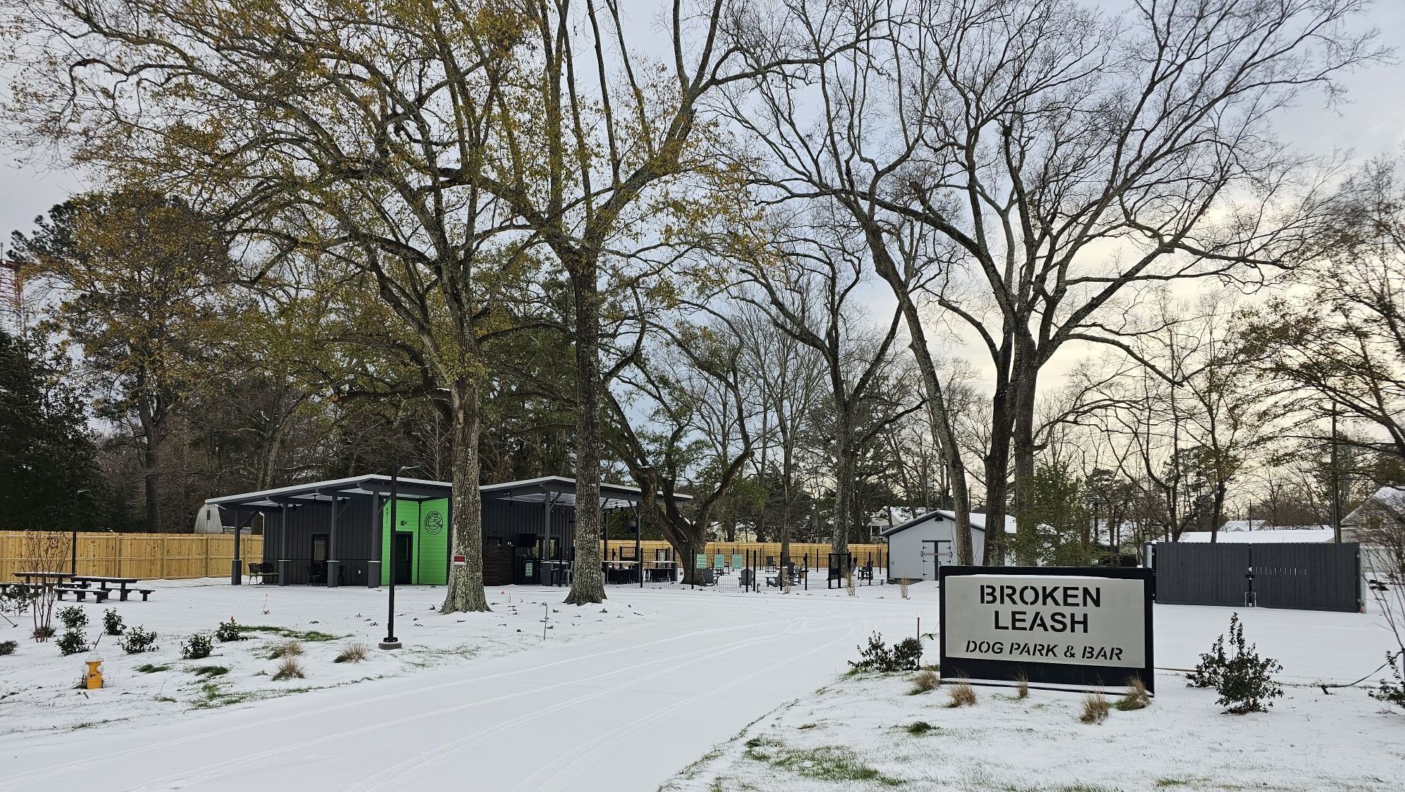 Broken Leash Dog Park in North Charleston covered in snow, showcasing the building and outdoor play areas.